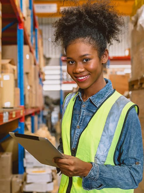 A business professional using a tablet among stocked warehouse shelves